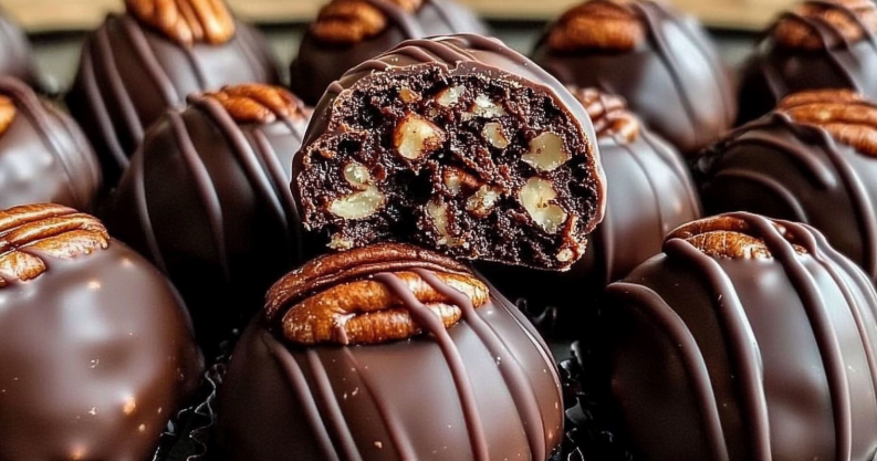 A platter of glossy Chocolate-Dipped Pecan Pie Balls garnished with crushed pecans, arranged on parchment paper in a cozy, festive kitchen setting.